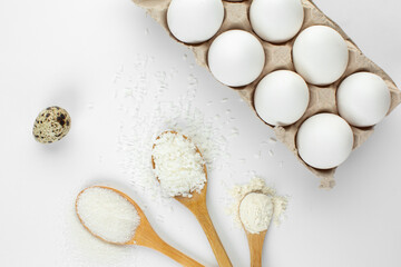 Eggs and quail eggs and sugar, coconut shavings in wooden spoons 