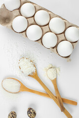 Eggs and quail eggs and sugar, coconut shavings in wooden spoons 