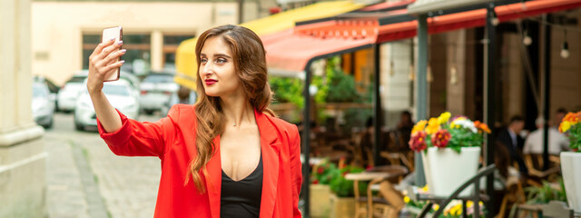 Fototapeta premium Beautiful young caucasian tourist woman takes a selfie in a European city