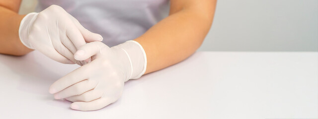 Two hands in white protective gloves of nurse or female doctor sitting at the white table