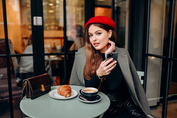Female blogger chatting with followers in social networks on modern smartphone using 5G internet connection.Hipster girl in watching video on website on cellular in cafe.