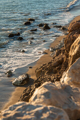 rocks, stones and waves on the shore of a beach at dusk
