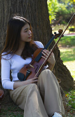 Young beautiful lady hold violin and bow in hand and looking to acoustic instrument