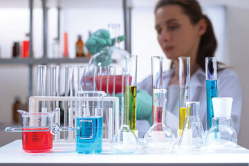 laboratory equipment, supplies, jars, bottles, cylinders, beakers, graduate, test-mixer, medicine-glass. Lab assistant holding bulb with red liquid in defocus