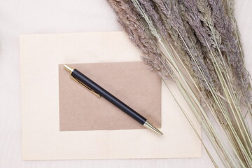 Czarno złoty długopis na beżowej kartce i suszone kwiaty  - obrazy, fototapety, plakaty