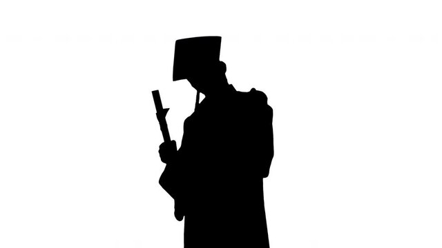 Silhouette Happy male student in graduation robe posing with his diploma and showing thumbs up.