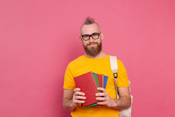 Adult student cheerful casual wear guy with beard and backpack holding books isolated on pink background