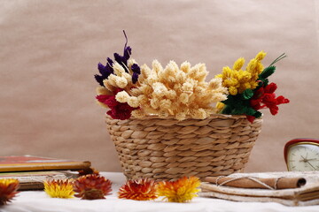 Koszyk wiklinowy z kolorowymi suszonymi kwiatami na beżowym tle