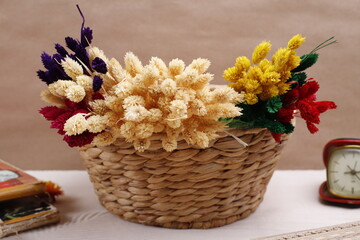 Koszyk wiklinowy z kolorowymi suszonymi kwiatami na beżowym tle - obrazy, fototapety, plakaty