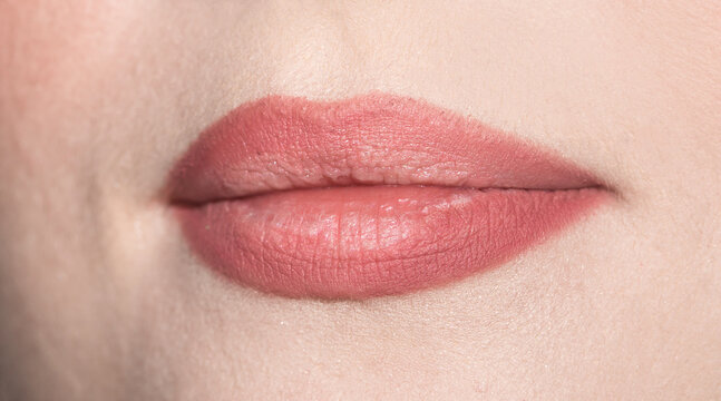 Lips of a girl close up. Makeup artist paints girl lips with a pencil and pink lipstick. Makeup for every day lipstick Krakoralovy color.