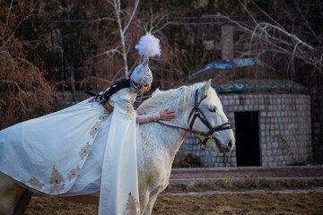 An Asian girl in a national costume is riding a horse. Kyrgyz national costume.