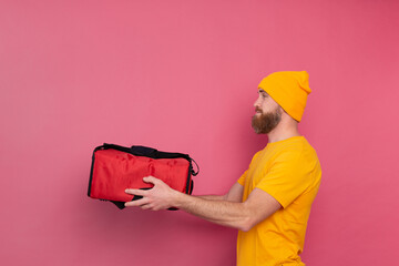 European bearded delivery man with box with food  pink background isolated