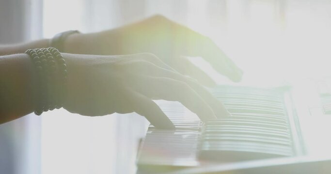 Piano keyboard with close-up of hands against a backlit background with yellow prism placed in front of the lens to distort image