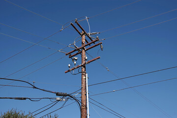 Low angle view of an electricity distribution pylon and power lines under blue sky