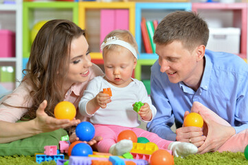 Parents playing with adorable little daughter at playroom