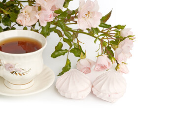 Pink marshmallows and roses. Tea time. Cup of black tea.