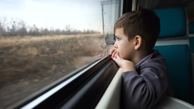 six-year-old boy rides a train and looks out the window. close-up