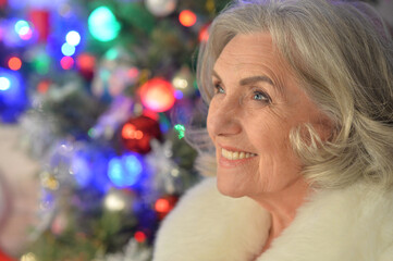 Happy smiling senior woman posing in fur coat on Christmas
