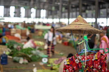 A hat and a dress hanging on a stick at a local market in Myanmar