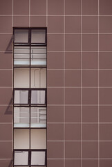 Row glass window panes in vertical line on brown aluminum composite tiles wall of modern office building