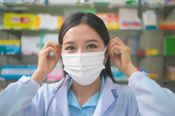 Portrait of asian woman pharmacist wearing a surgical mask in a modern pharmacy drugstore, covid-19 and pandemic concept.