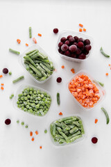 Frozen vegetables in transparent containers on white background