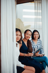 Creative work of female designers. Three asian girls in formal clothing pose on doorstep looking at camera and smiling.