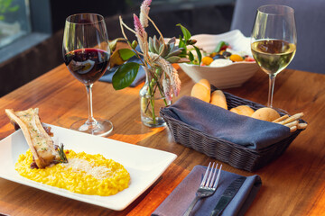 Italian yellow risotto with bone hole meat Homemade Roasted Beef Bone Marrow with Thyme and Lemon. A portion of risotto and marrow bone with wine. Gourmet food