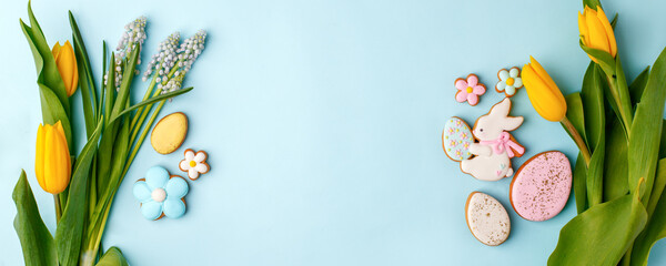 Easter floral background, various gingerbread glazed cookies end decorated with natural botanical elements on blue, flat lay, view from above, blank space for greeting text, banner, flyer, coupon