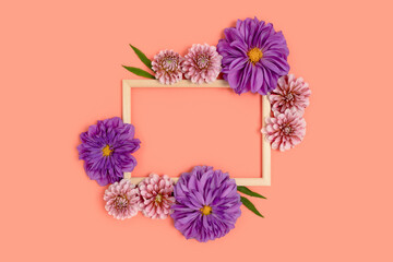 Top view of flower border frame made of dahlia on a coral color background. Greeting card for 8 March with copyspace. Nature concept.