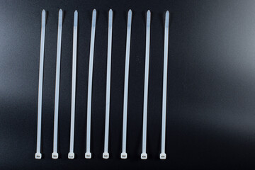 White plastic ties for cables. Ties for cable on black background.