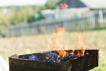 defocused orange flame of a campfire for barbecue in summer on green grass background