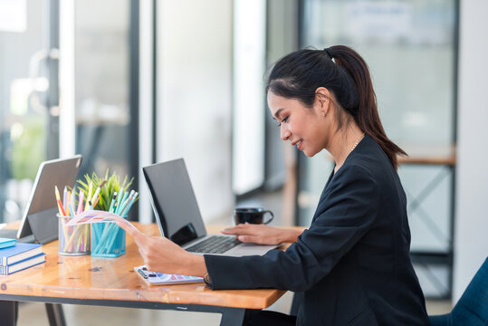 Side View Of Asian Businesswoman Working By Using A Laptop With Documents At The Office.