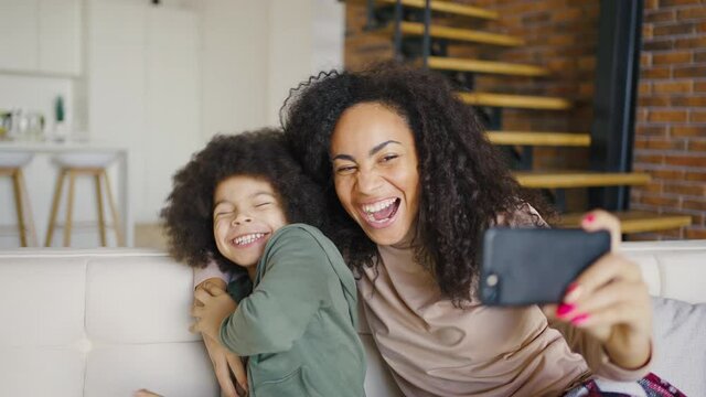 Young woman and her little son taking selfie. Happy mother with her kid sitting on a sofa