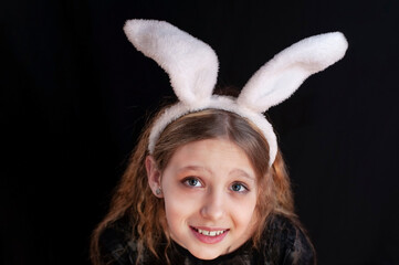 Easter bunny on a dark background - young girl sincerely smiling with bunny ears on his head, Easter concept