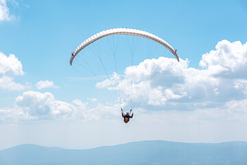 Paraglider against the blue cloudy sky. The paraglider flies in the sky.