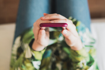 Mobile phone in woman's hands, shot from above with thin depth of field. Female person holding a smartphone in hands