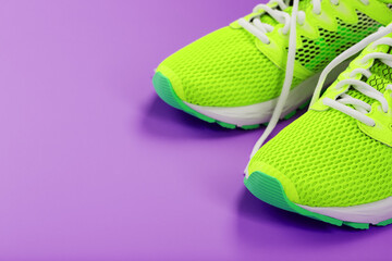 Green running shoes on a purple background.