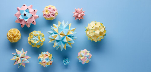 Set of multicolor handmade modular origami balls or Kusudama Isolated on blue background. Visual art, geometry, art of paper folding, paper crafts. Top view, close up, selective focus, copy space.