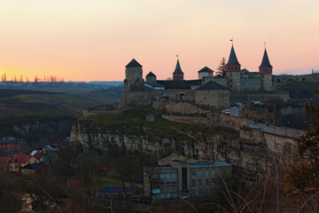 Obraz premium Awesome aerial landscape view of the old Kamianets-Podilskyi fortress. Panoramic sunset sky in the background. Famous touristic place and travel destination in Ukraine.Concept of landscape and nature