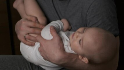 Father lulling to sleep his little son. Toddler baby boy lying in father's arms. Father's day, parenthood concept.