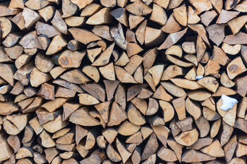 Stacked stack of firewood. Large woodpile with chopped wood. Stacked stack of firewood from the end.