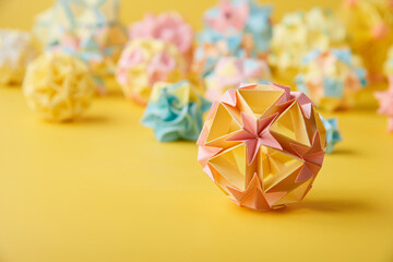 Set of multicolor handmade modular origami balls or Kusudama Isolated on yellow background. Visual...