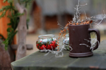 Summer composition on a wooden table made of berries, fir branches and a ceramic mug.