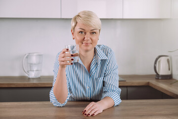 Woman holding glass with water in kitchen in morning