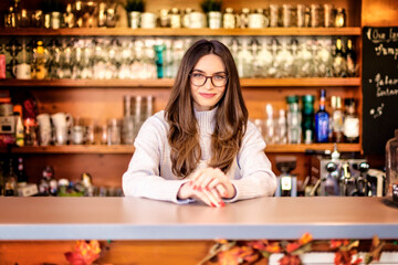 Small business owner young woman standing behind the counter in the cafe