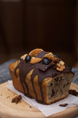 Obraz na płótnie Canvas Banana bread garnished with nuts and dried fruits. A slice of bread is visible. Close-up shot.