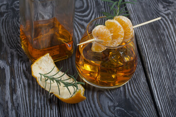 Alcoholic cocktail. Garnished with rosemary slices and tangerine wedges. Close-up shot.