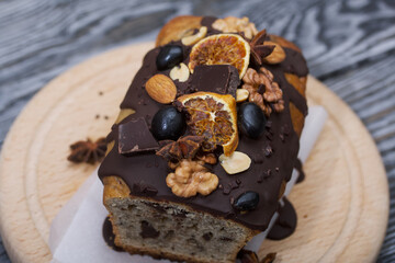 Banana bread garnished with nuts and dried fruits. A slice of bread is visible. Close-up shot.