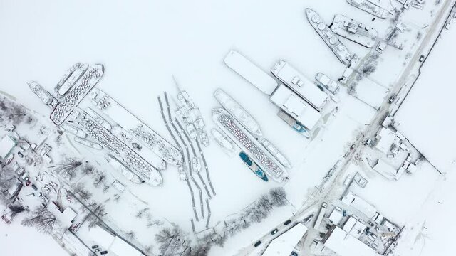 River harbor Ships blocked with ice of frozen river. Aerial of industrial city Block covered with heavy snow.